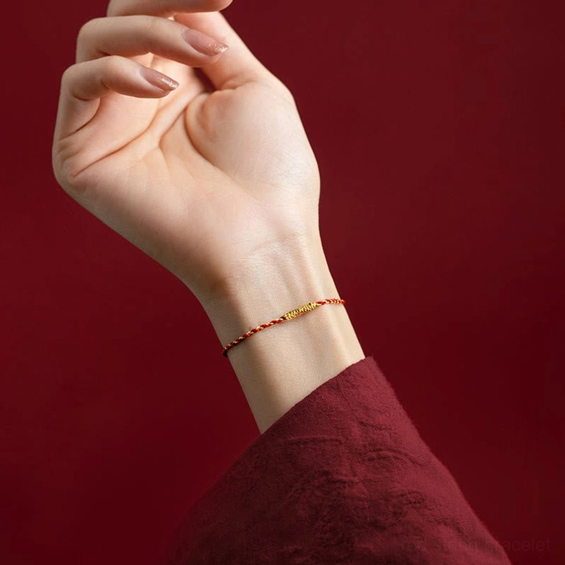 Red string bracelet with gold accents worn on model wrist, minimalist fit