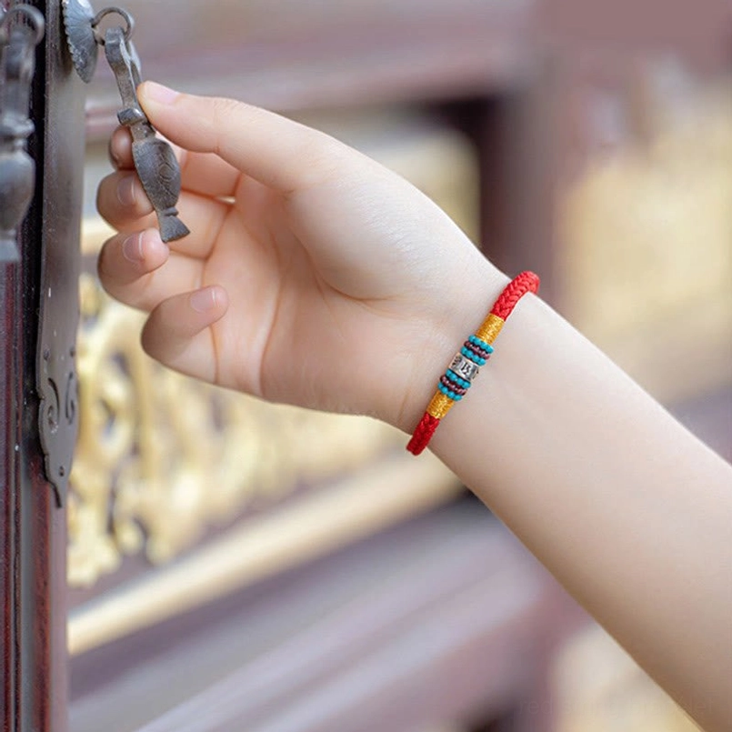 Red string bracelet with gold winding and turquoise bead detail