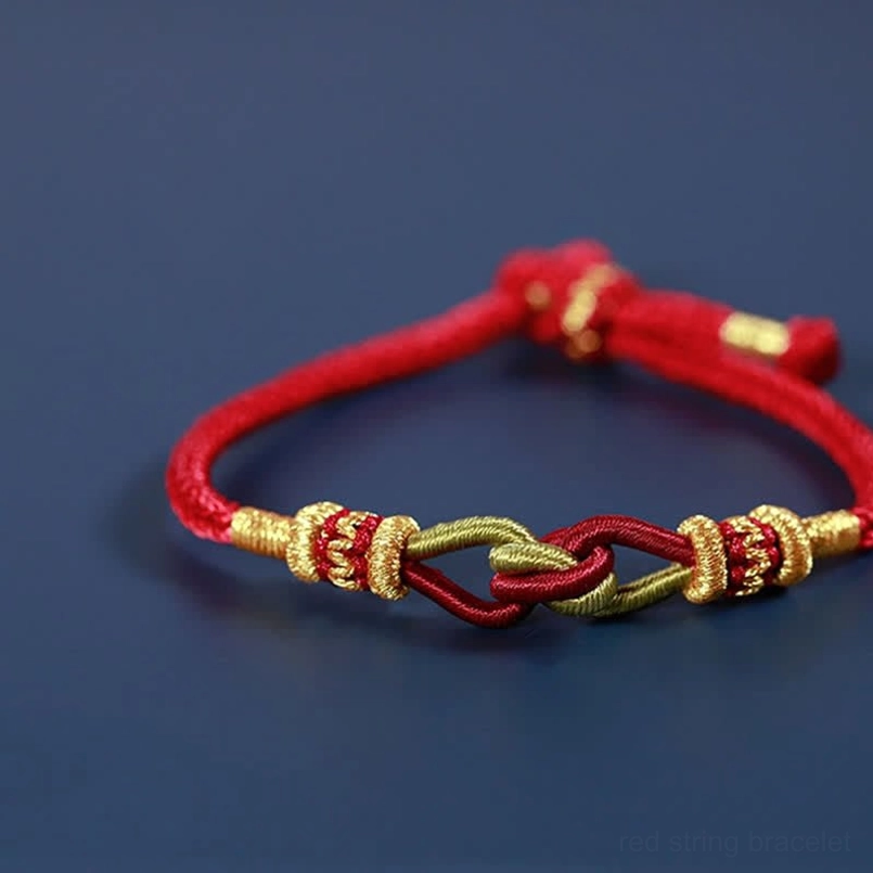 Handmade braided red string bracelet with gold and green woven details