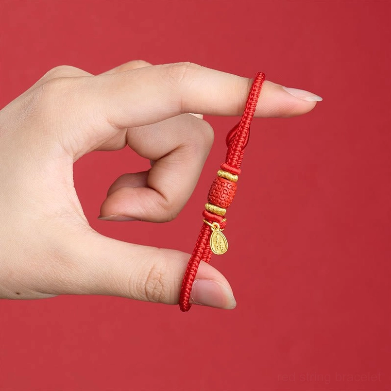 Adjustable red string protection bracelet held in hand showing braided rope and copper hardware