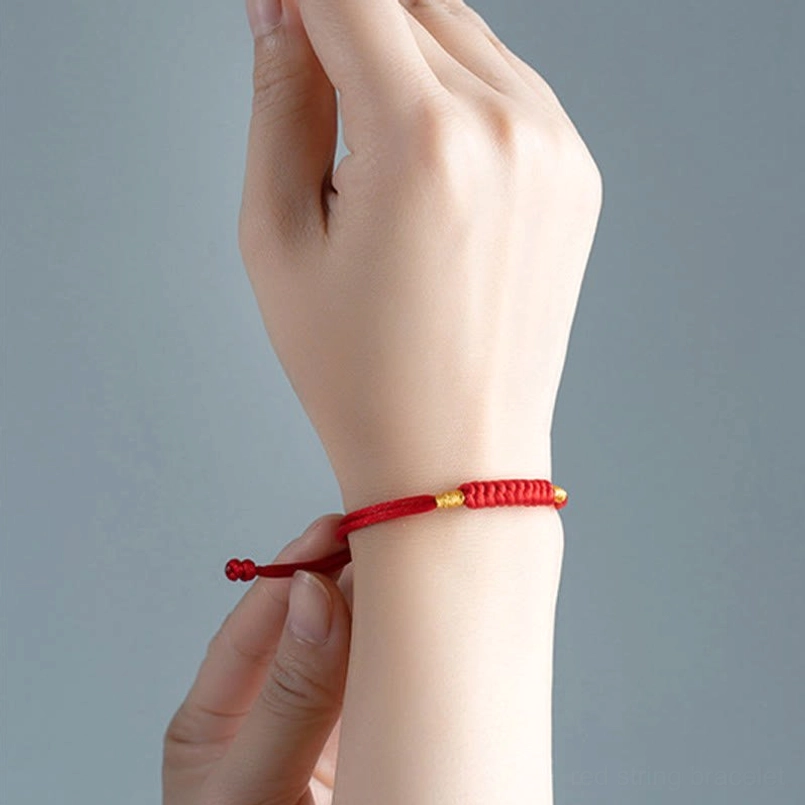 Red string lucky knot bracelet worn on hand close up adjusting pull cord