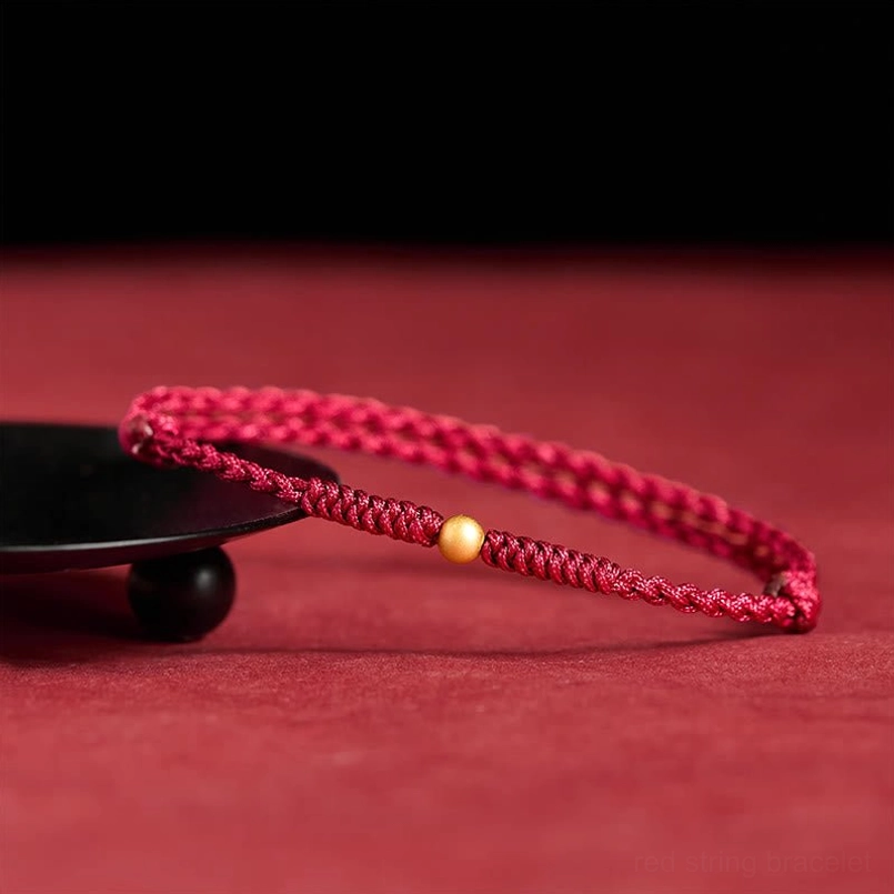 Handmade red braided bracelet with gold charm bead, professional shot