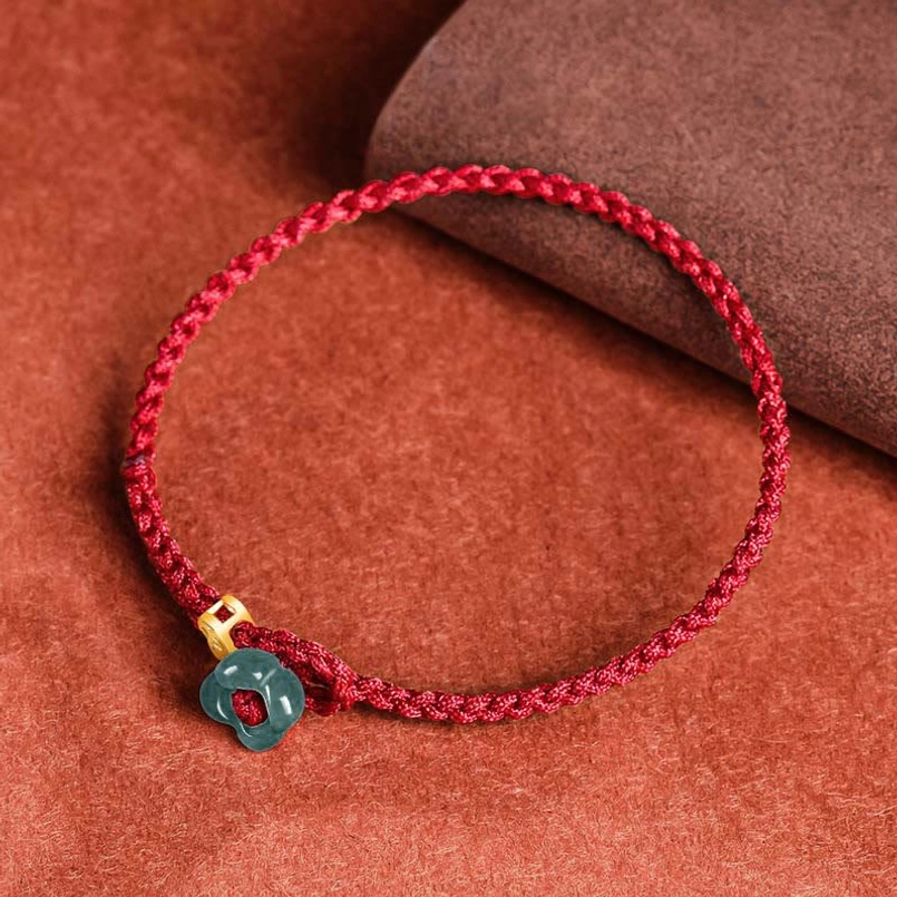 Minimalist red string bracelet with single jade and coin charm flat lay