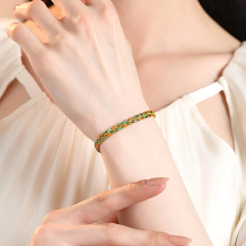 Thin multicolor braided red string bracelet worn on female wrist with white elegant outfit, lifestyle flat lay demonstrating everyday wear