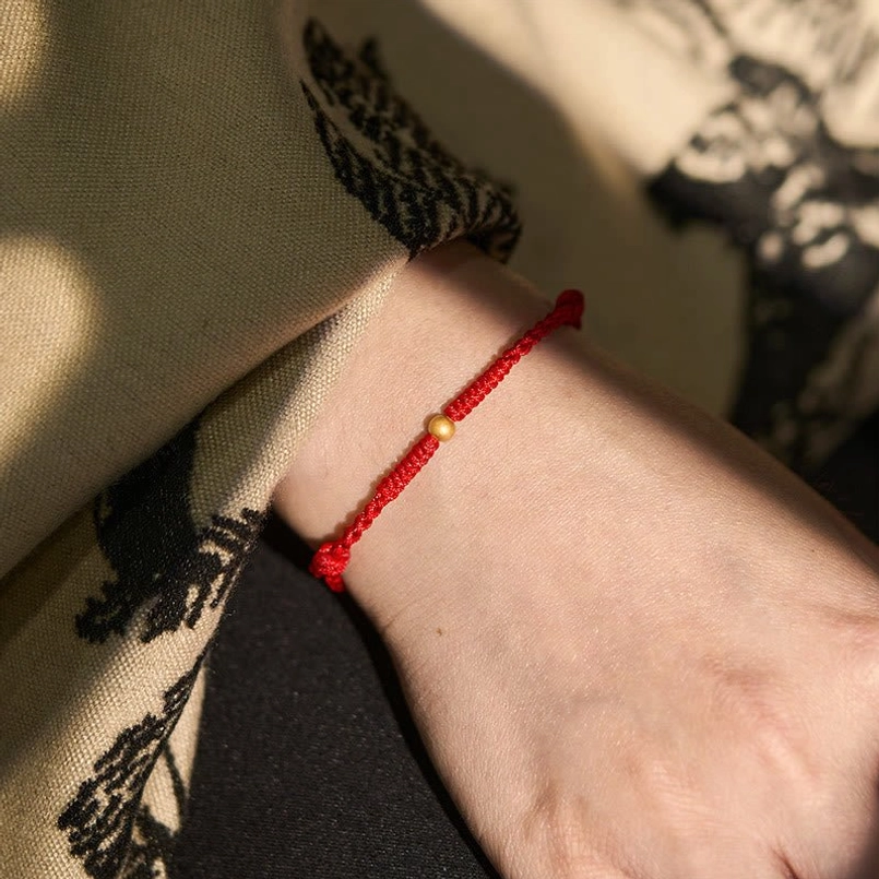 Red string bracelet on velvet, luxury presentation with gold charm