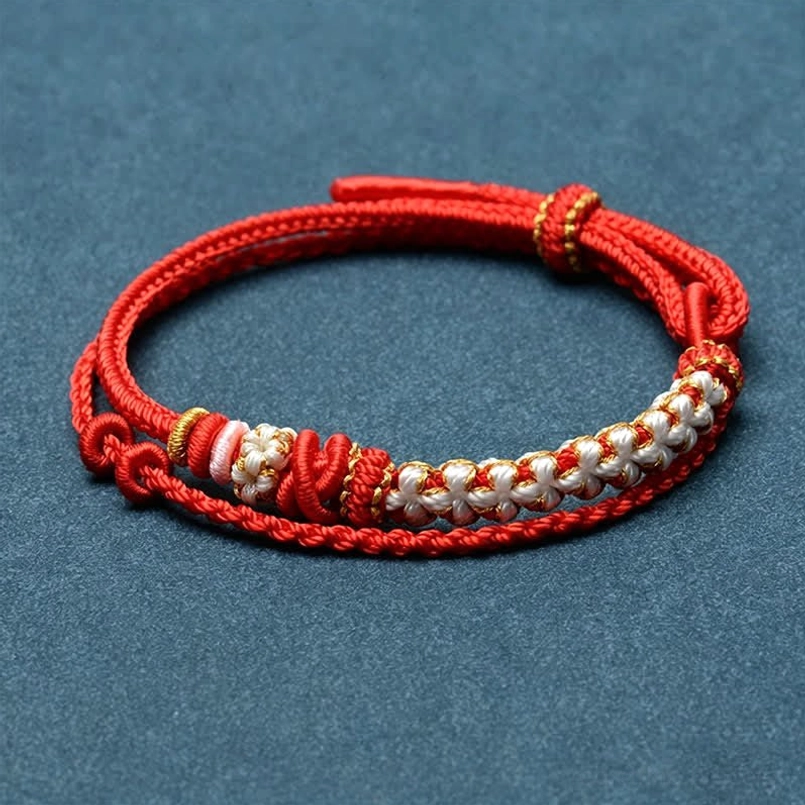 Multicolor woven red string bracelet with decorative knots on blue fabric background