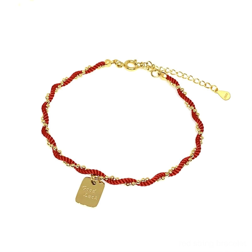 Red string luck bracelet product shot placed on natural stone background