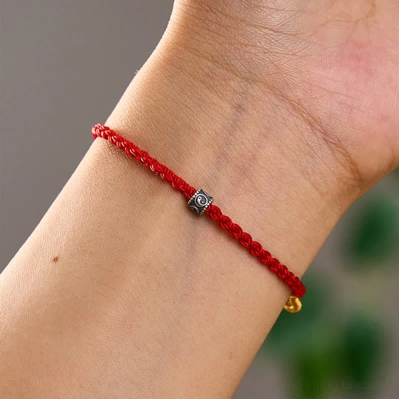 Red string Yin Yang protection bracelet worn on wrist showing fit and silver charm