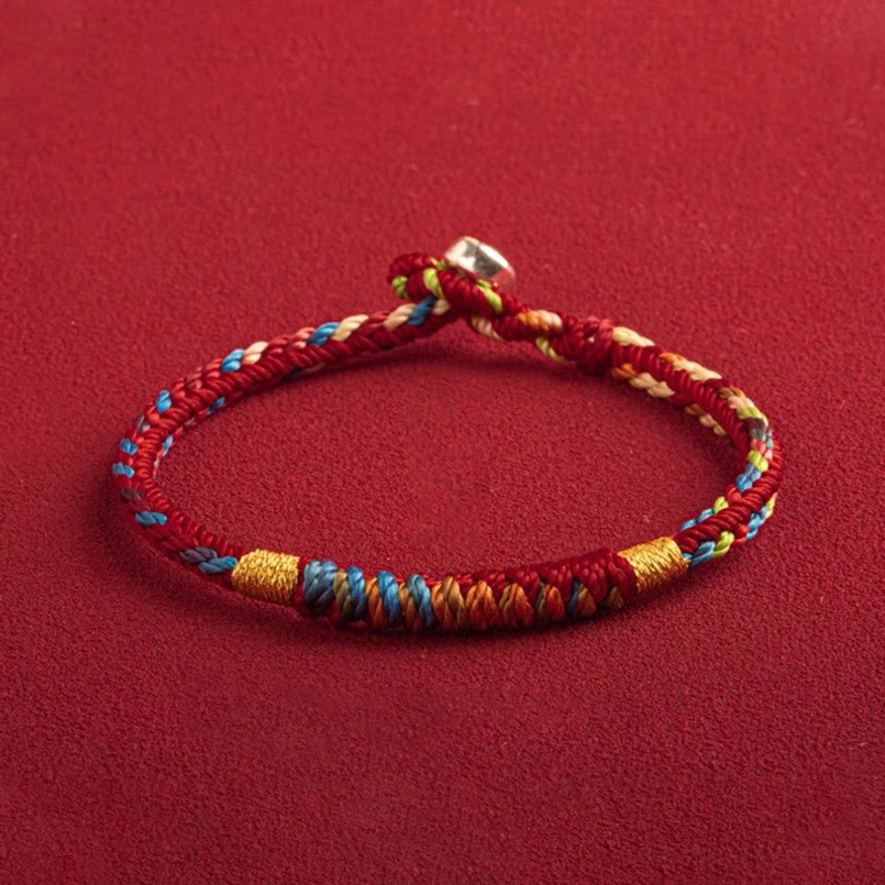 Red string protection bracelet overhead view showing blue and gold woven accents