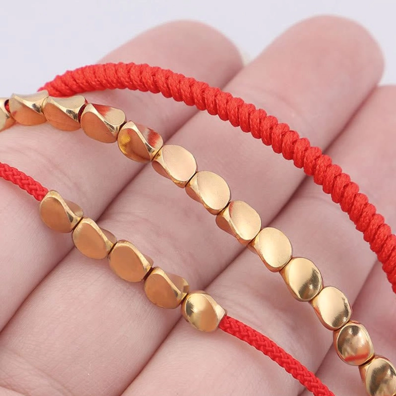 Red string copper bead bracelets in palm hand flat polished copper beads display