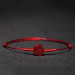 Red string blessing bracelet with plum blossom charm flat lay