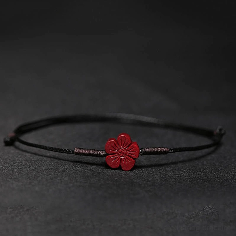 Red string bracelet with plum blossoms charm detail shot