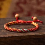 Red string protection bracelet handwoven with colorful threads and wooden bead adjuster, close-up view