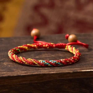 Red string protection bracelet handwoven with colorful threads and wooden bead adjuster, close-up view
