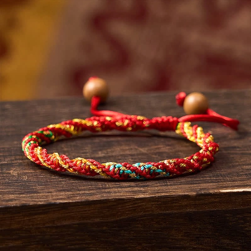 Red string protection bracelet handwoven with colorful threads and wooden bead adjuster, close-up view
