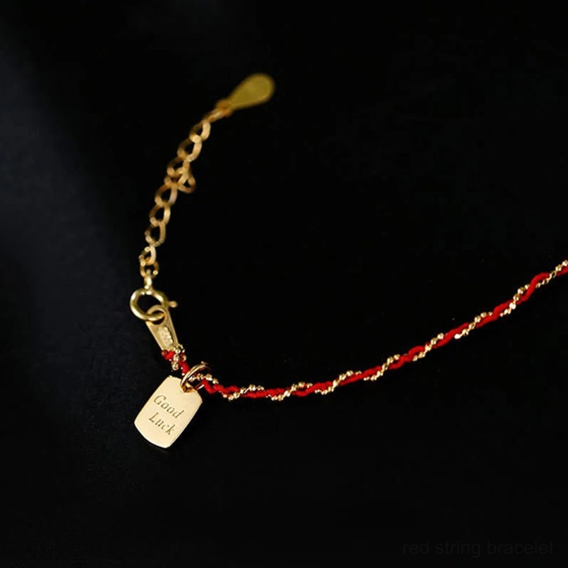 Red string bracelet with gold extension chain and engraved rectangular good luck tag