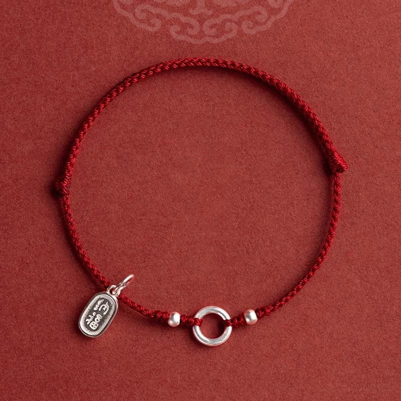 handmade red string bracelet with engraved silver oval pendant close-up
