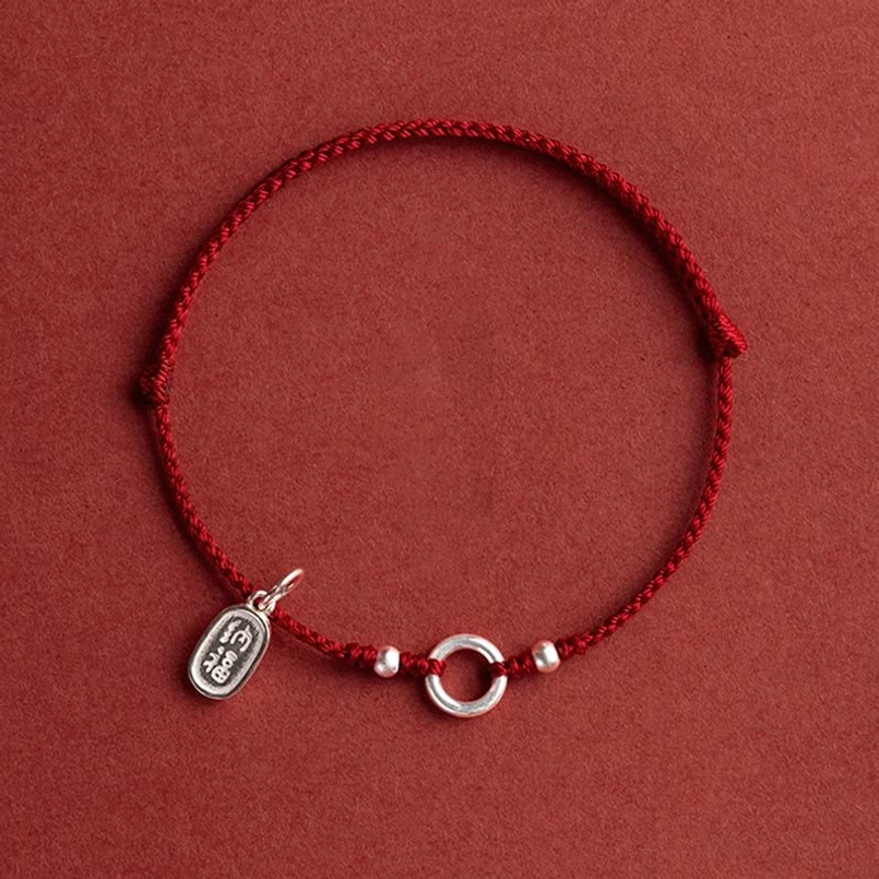red string bracelet with silver ring beads and engraved charm flat view