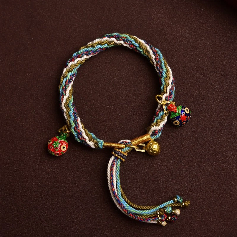 Hand braided red string bracelet with long tassel ends on solid dark brown background