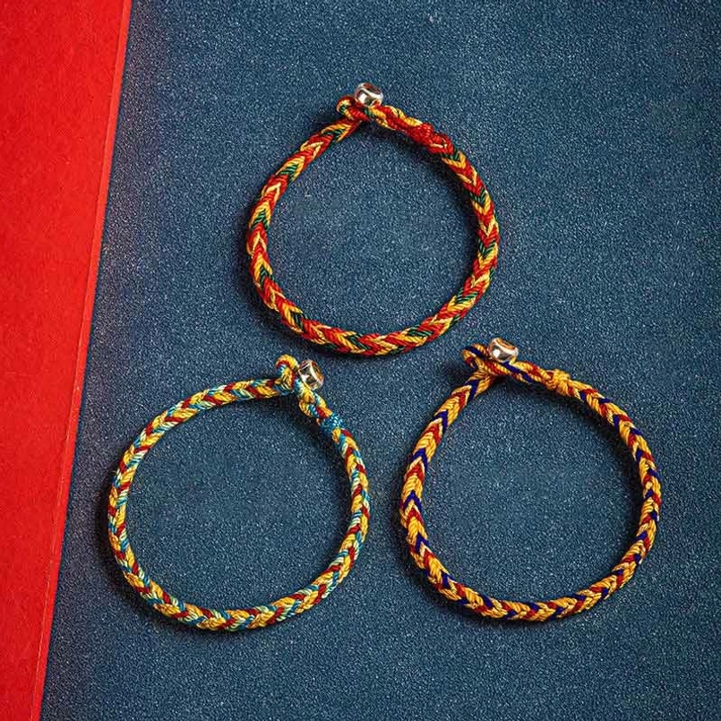 Three multicolor red string bracelets displayed side by side showing color variations including orange dark green red and orange dark blue red styles