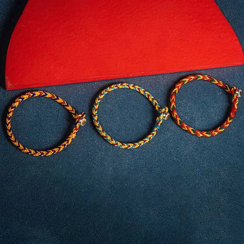 Three handcrafted multicolor red string bracelets with woven texture detail arranged on contrasting background