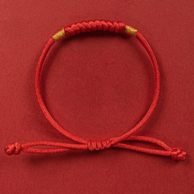 Red braided lucky knot bracelet flat top view with gold bead accents on red background
