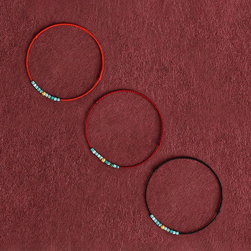 Multiple red string bracelets with turquoise gold beads shown in red and black rope variations