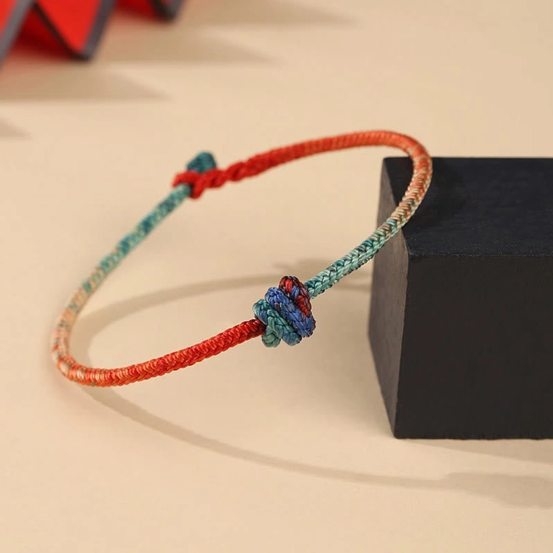 Close-up of red and teal dual-color hand-woven bracelet showing detailed weave texture