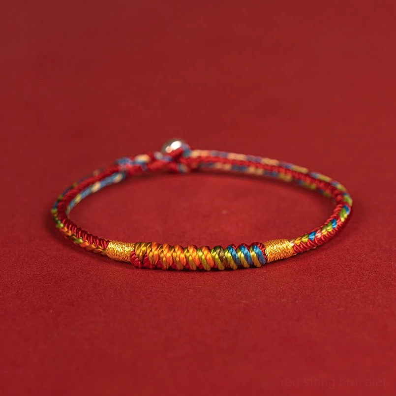Multicolor red string bracelet placed next to spiritual crystal stones for display