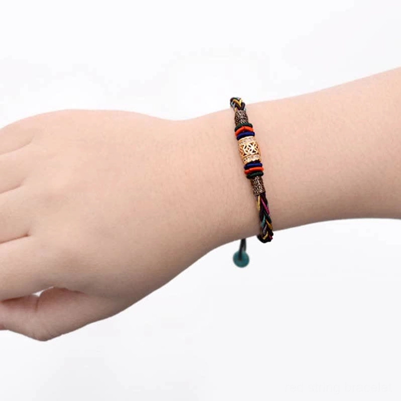 Tibetan red string bracelet worn on wrist with copper coin charm