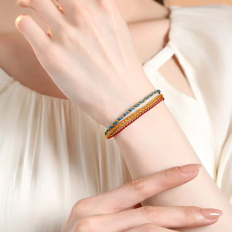 Woman wearing adjustable braided red string bracelet with multiple colors on wrist, close-up detail view