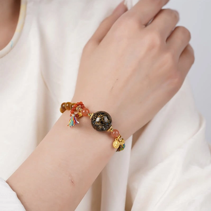 Tibetan lacquer tiger eye red string bracelet worn on wrist close up showing tassel detail
