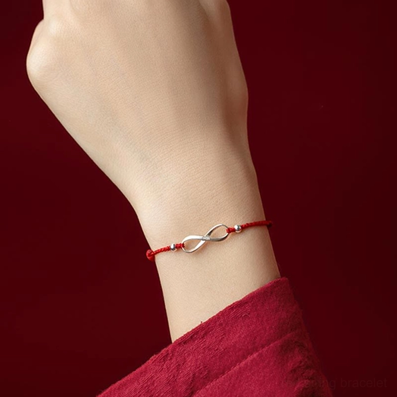 Red string protective bracelet worn on wrist showing endless knot charm