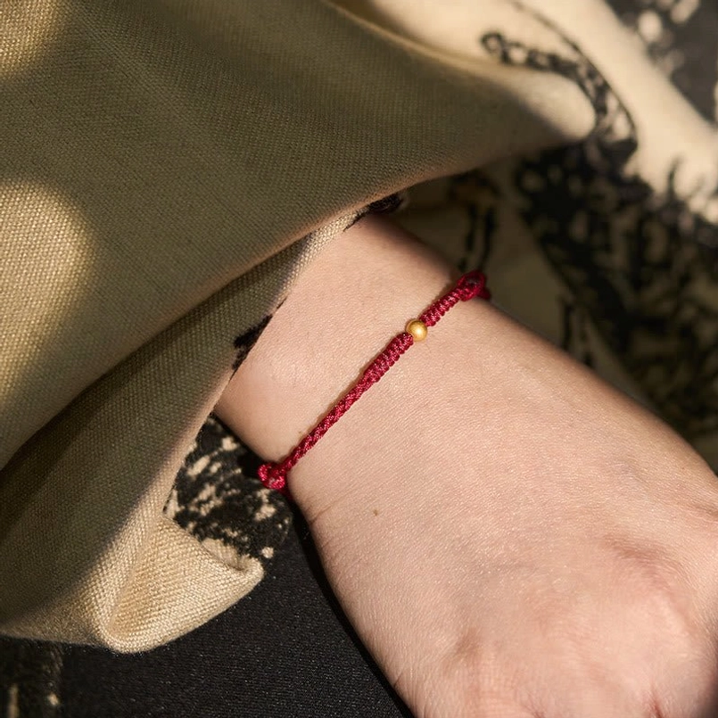 Red string bracelet worn on wrist, showing fit and comfort