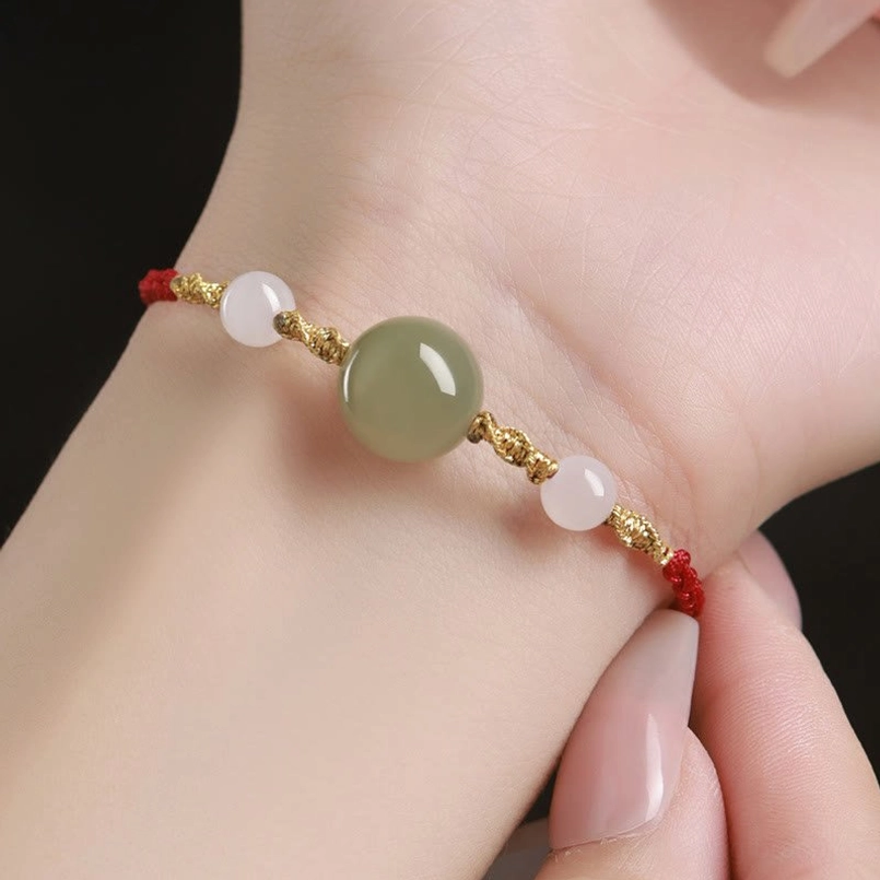 Red string luck bracelet worn on left wrist, close-up wearable view