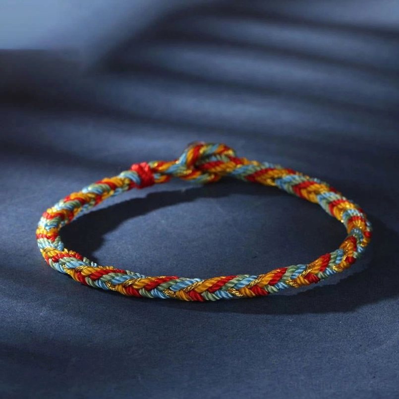 Close-up view of multicolor red string bracelet woven texture with balanced orange dark green red color combination