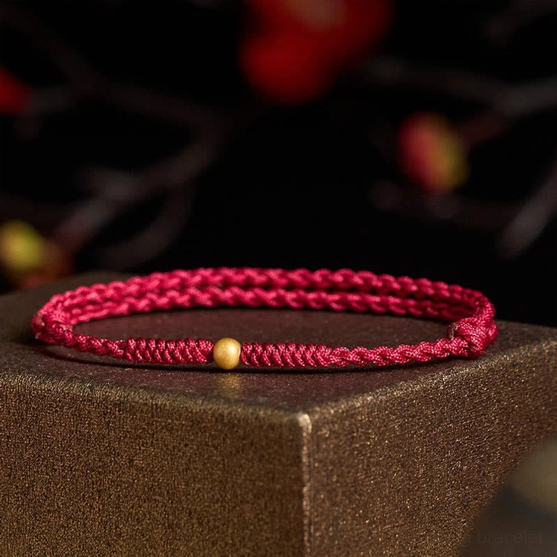 Woven red string bracelet with gold accent bead, close-up texture view