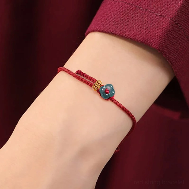 Red string bracelet on wrist showing natural fit and charm positioning