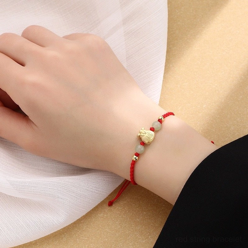 Red rope lucky bracelet worn on wrist close-up with adjustable knot and jade spacer beads