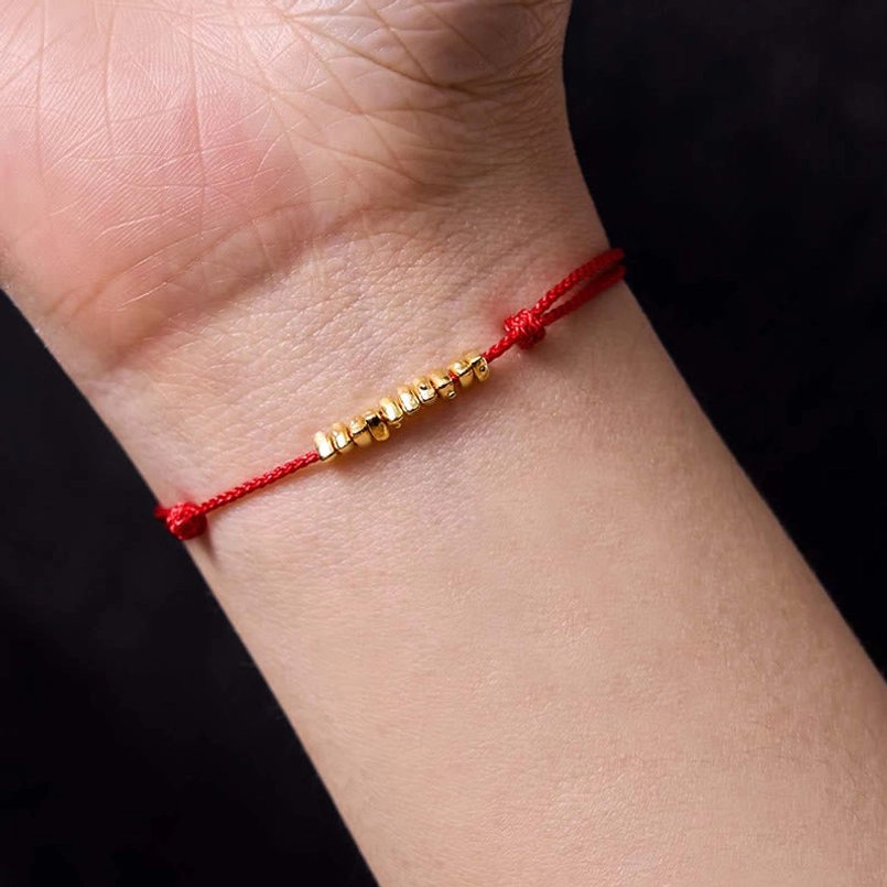 Red string protection bracelet worn on wrist showing adjustable fit