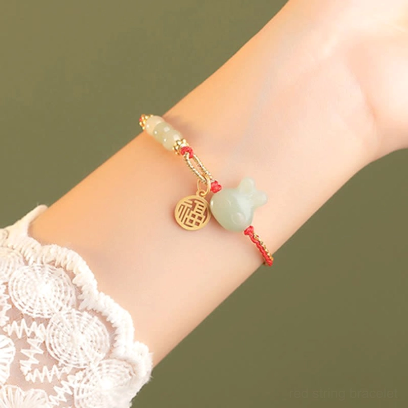 Rabbit zodiac red string bracelet worn on wrist with white lace sleeve
