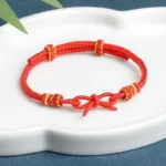 Red string butterfly bracelet with gold accents and adjustable bow knot design