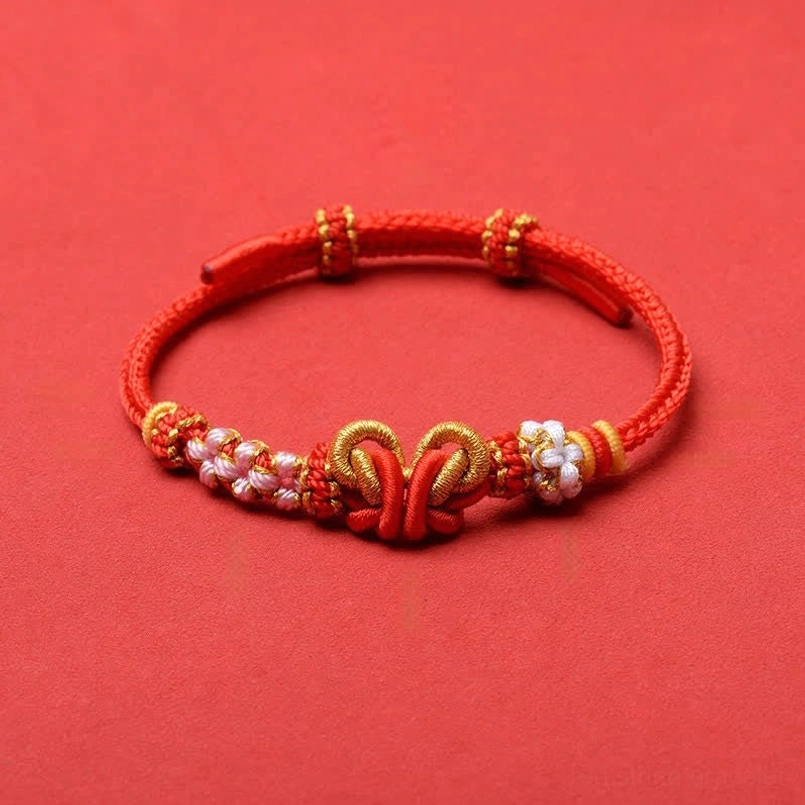 Red braided adjustable red string butterfly bracelet with gold knot and flower beads close-up