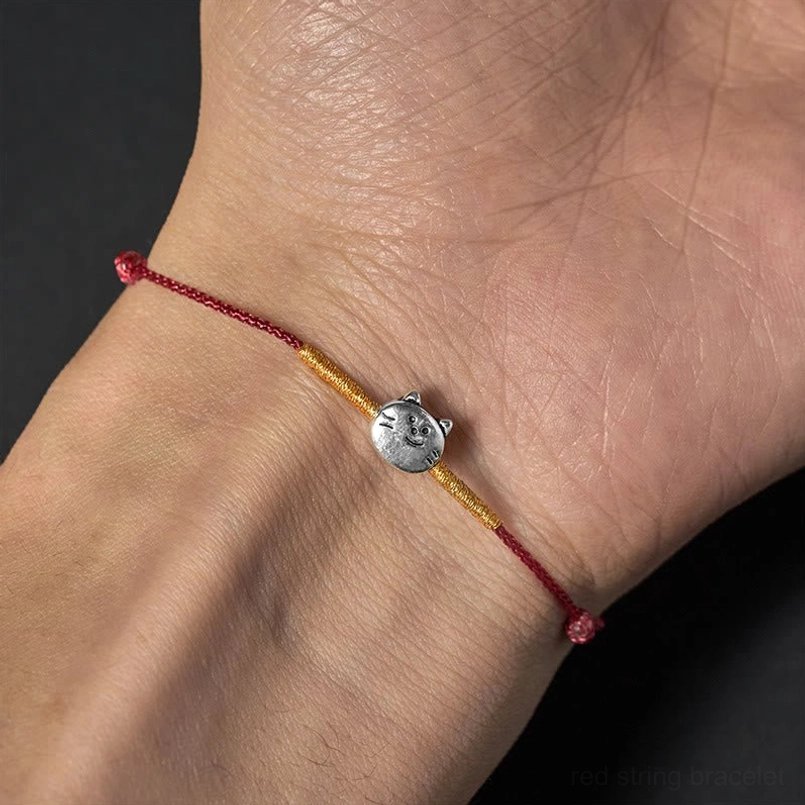Sterling silver cat bracelet worn on wrist showing red woven cord and adjustable knot