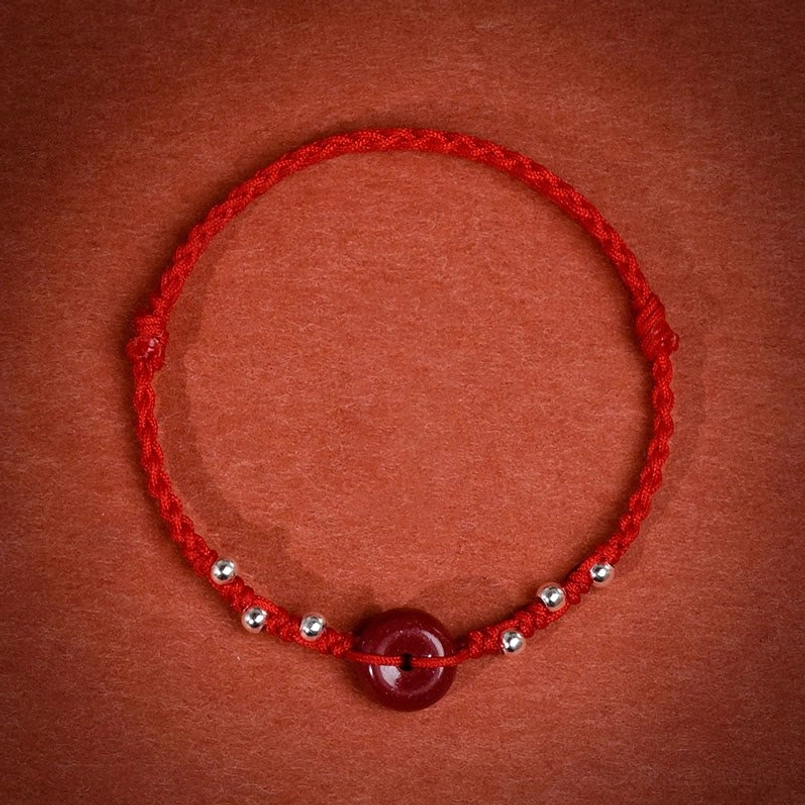 Red string cinnabar peace buckle bracelet front view with braided cord and sterling silver accents
