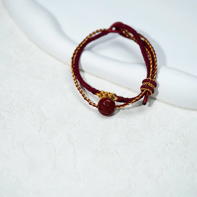 Adjustable red string cinnabar blessing bracelet side view on curved display rod
