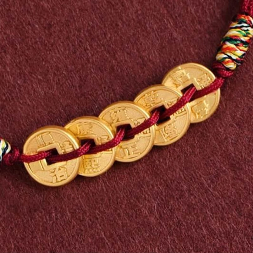 Side close-up of five coin bracelet segment showing visible coin characters and multi-color braided knot