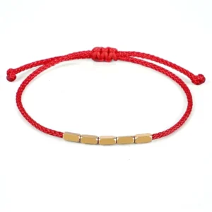 Red string copper bead bracelet with adjustable sliding knot, flat lay view