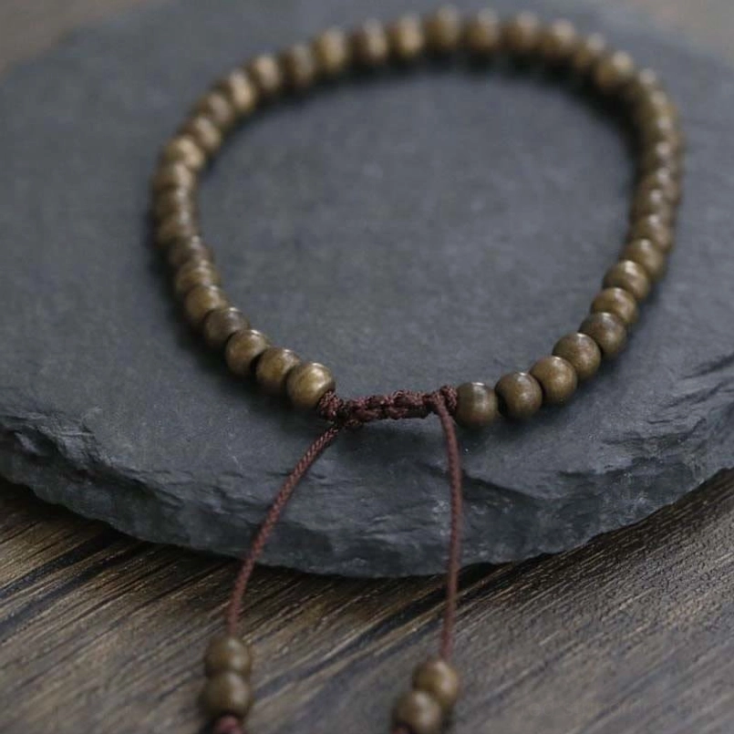 Red string bracelet with copper beads side view on wood and stone tabletop