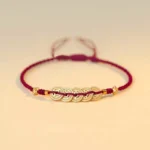 Burgundy red string copper coin fortune tree braided bracelet flat lay - handmade lucky bracelet
